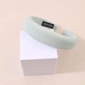 Padded mint green sponge headband with handmade label on minimalist stand