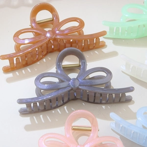 Dettaglio macro di mollettoni a fiocco perlati in colori macaron con molle in metallo