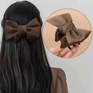 Vue détaillée d'une grande pince à cheveux avec nœud marron mat sur une queue de cheval