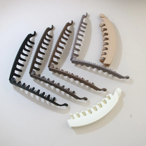Group of matte banana hair clips in six neutral colors arranged on grey background