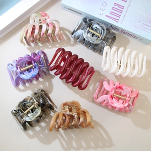 Set of seven marble and solid color ABS hair claws displayed on a warm beige background