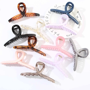 Flat lay detail of 13cm crisscross hair claw clips in various colors on ceramic plate