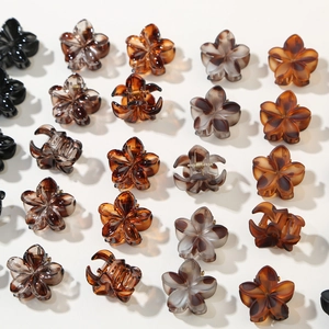 Detailed top view of 12 mini floral hair claws in black, amber, and marble resin