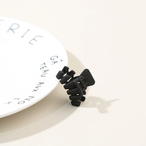Close-up of matte black geometric hair claw clip on white decorative ceramic plate