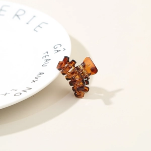 Close-up of amber resin mini hair claw clip with shell texture and metal spring