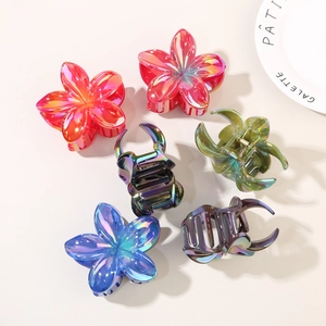 Dettaglio di sei mollette per capelli iridescenti con colori sfumati e forme di fiori