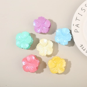 Flat lay of small colorful hibiscus flower hair claws in six soft pastel pearlized shades