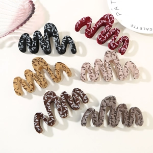 Detail of six velvet hair claws with white leaf patterns and unique wavy wave design