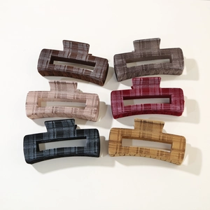 Flat lay of six flocked plaid hair claw clips in autumn colors on a beige surface