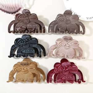 Macro detail of six clover shaped hair claws with wavy wood grain texture in varied colors
