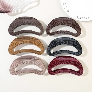 Detail showing various colors of velvet moon-shaped hair claws with wood grain texture