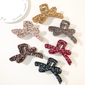 Flat lay of leopard print velvet bow hair claws in six colors on beige background