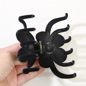 Detail of a large clover flower hair claw clip with flocking matte black texture and metal spring