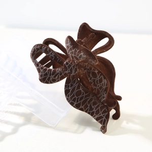 Close-up of a brown flocked butterfly hair claw with silver patterns and matte finish