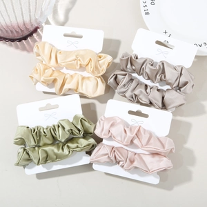 Detail view of satin scrunchies set in elegant Morandi colors with bow-tie packaging