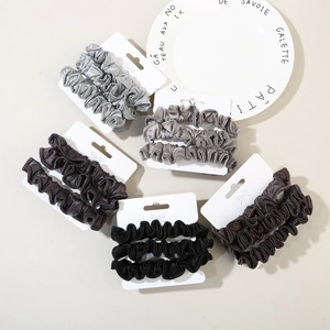 Detailed view of satin scrunchies in neutral tones showing pleated texture and silky sheen