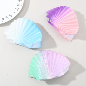 Detailed view of iridescent shell-shaped hair clips in gradient blue, purple and green colors