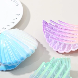 Flat shell-shaped hair claws with pearl iridescent gradient finish for elegant hairstyles