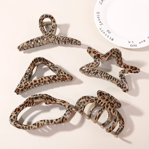 Flat lay of retro leopard print hair claws in various geometric shapes on a beige surface
