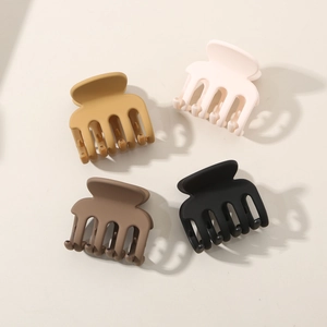 Close-up of four matte hair claws in cream, yellow, brown and black for women