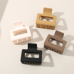 Flat lay of four matte square hair claws in cream, yellow, caramel and black tones
