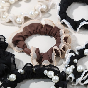 Detailed shot of elastic silk-like scrunchies with faux pearls in beige and black