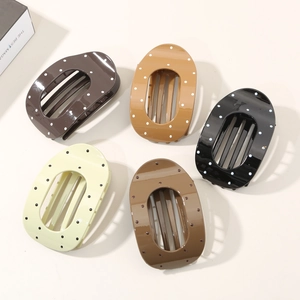 Five assorted polka dot oval hair claws in brown, black, and cream resin colors