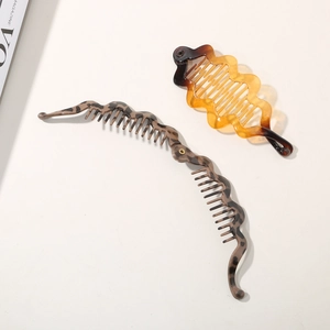 Detail of tortoise shell and amber resin banana hair clips with wave-edged design