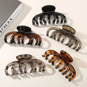 Detailed view of five large pumpkin shaped hair claws in assorted glossy marble finishes