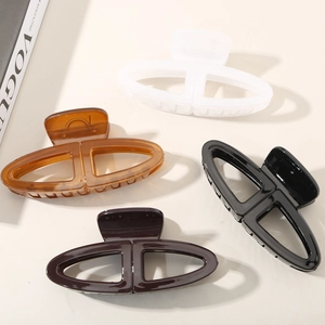 Flat lay of four elegant oval hollow hair claws in white, amber, black, and brown colors