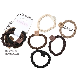 Detail of five woven elastic hair ties in neutral tones with handmade smiley leather labels