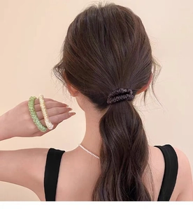 Detail of satin silk scrunchies in brown, green, and cream on a elegant ponytail