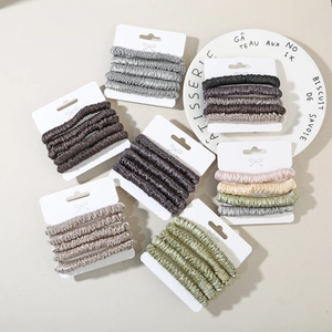 Close-up of elegant silk satin scrunchies set in earth tones on display card