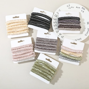 Detailed view of elastic silk-like scrunchies in various colors on display cards