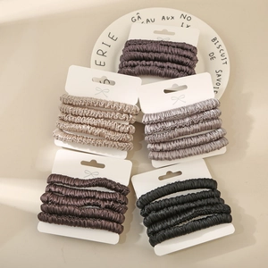 Close-up of silk-like scrunchies set in five colors on elegant white bow card holders