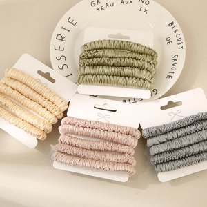 Close-up of four-piece glossy pleated silk scrunchie sets in various elegant colors