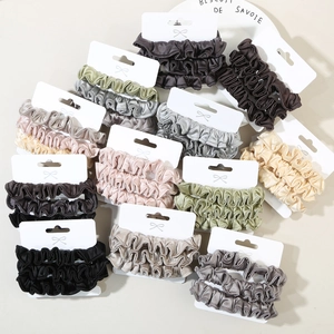 Close-up of elastic satin silk scrunchies in Morandi colors on cardboard display cards
