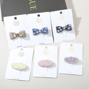 Close-up of colorful rhinestone oval and bow hair clips on a white display card