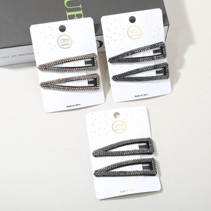 Detail of three pairs of rhinestone hair clips with black and champagne stones on cards