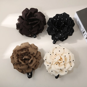 Flat lay of four fabric floral hair clips in brown, black, khaki and cream with polka dots