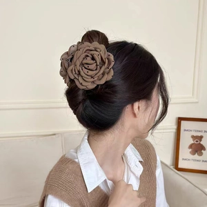 Detail shot of a large brown polka dot flower hair claw clip worn on a low ponytail