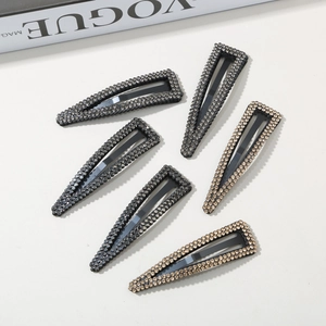 Detailed view of six rhinestone BB clips in black and champagne gold on a Vogue magazine