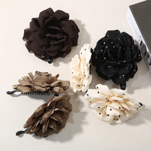 Flat lay of floral polka dot banana hair clips in dark brown, black, cream and beige