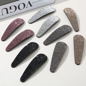 Flat lay of ten sparkling rhinestone teardrop hair clips set next to a fashion magazine