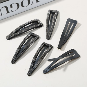 Set of 6 black metal teardrop hair clips with sparkling rhinestones on beige background