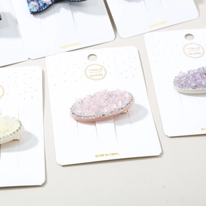 Detail view of handmade crystal rhinestone hair clips on a white display card