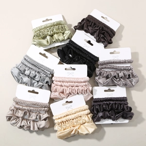 Three-piece satin scrunchies set in various colors on display cards for hair styling