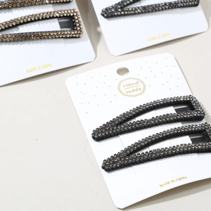 Close-up of handmade rhinestone hair clips in rectangular and water-drop shapes on display card