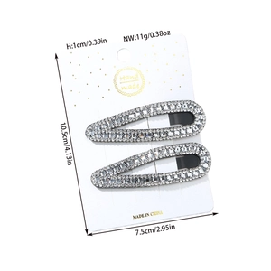 Detailed view of two sparkling rhinestone hair clips on a white presentation card