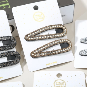Detailed view of handmade rhinestone water drop hair clips on white display cards